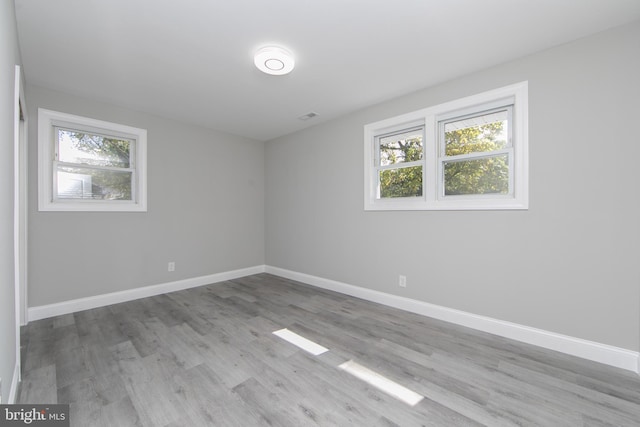 unfurnished room with visible vents, light wood finished floors, and baseboards