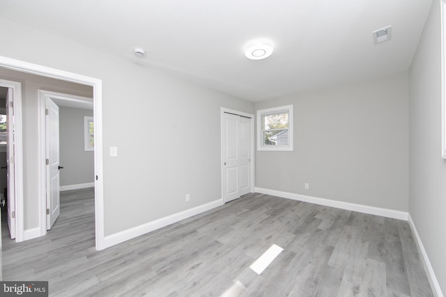 unfurnished bedroom with baseboards, a closet, visible vents, and light wood-style floors