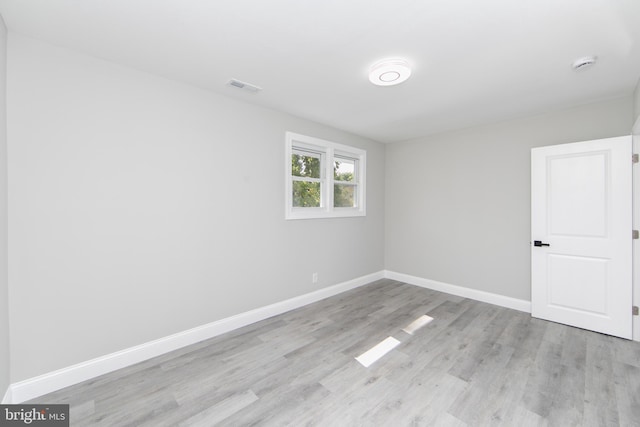 empty room with light wood-style flooring, visible vents, and baseboards