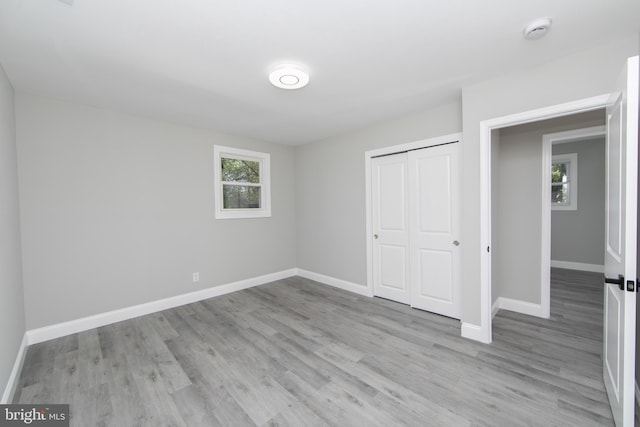 unfurnished bedroom featuring a closet, light wood finished floors, and baseboards