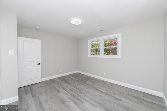 empty room featuring light wood-style floors, visible vents, and baseboards