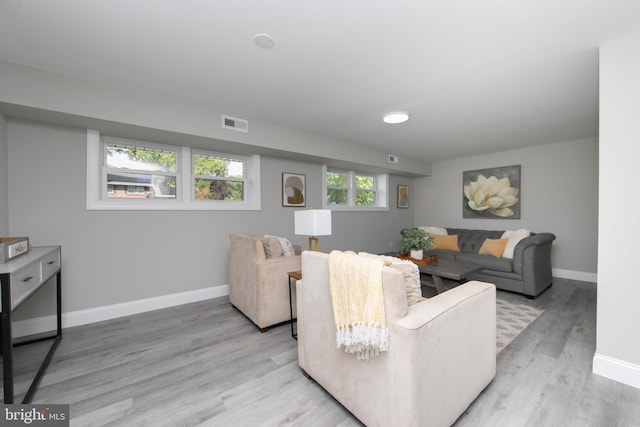 living room with light wood finished floors, visible vents, and baseboards