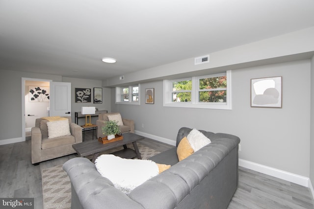 living area featuring baseboards, visible vents, and light wood-style floors