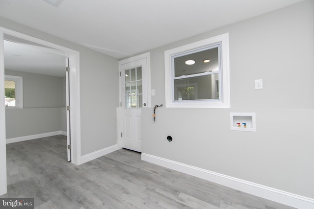 clothes washing area featuring hookup for a washing machine, laundry area, light wood-style flooring, and baseboards