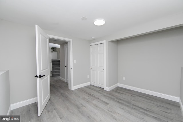 unfurnished bedroom featuring a closet, light wood-type flooring, and baseboards