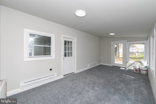 spare room with a baseboard heating unit, dark colored carpet, and baseboards