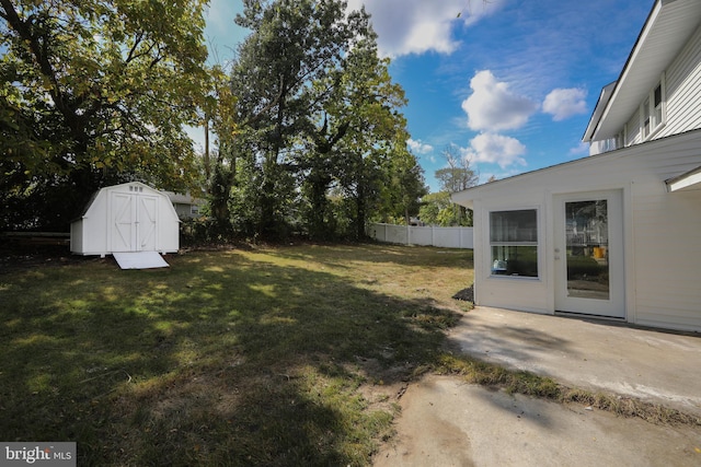 view of yard with a patio, fence, an outdoor structure, and a storage unit