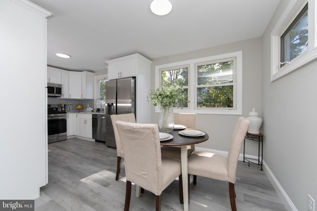 dining room with baseboards, light wood-style floors, and a healthy amount of sunlight