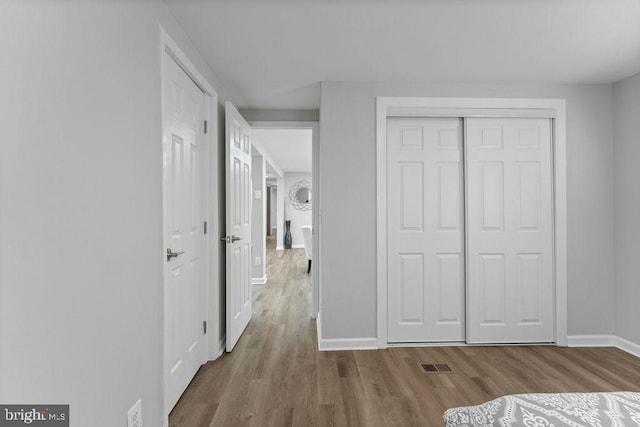 unfurnished bedroom featuring baseboards, visible vents, and light wood-style floors