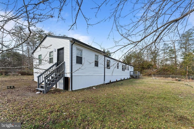 view of side of property featuring entry steps, a lawn, and fence