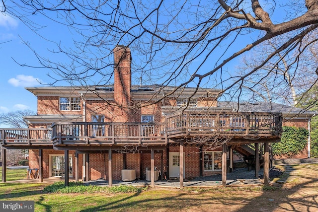 rear view of property with a wooden deck, a chimney, stairs, and brick siding