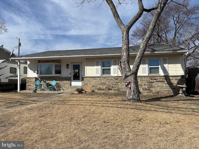 ranch-style house with stone siding and a front lawn