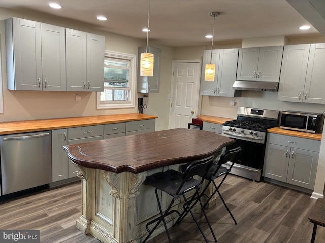 kitchen with under cabinet range hood, stainless steel appliances, dark wood-style flooring, wooden counters, and gray cabinets