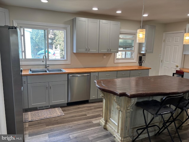 kitchen with butcher block countertops, stainless steel appliances, gray cabinetry, a healthy amount of sunlight, and a sink