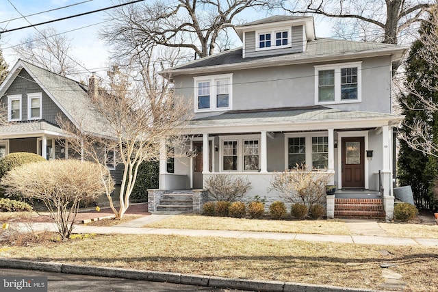 traditional style home featuring covered porch, a shingled roof, and stucco siding