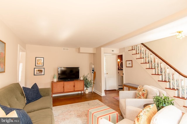 living area with stairway, wood finished floors, and visible vents