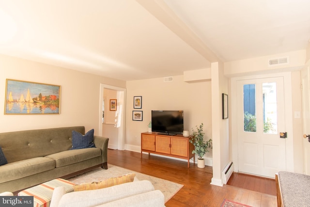 living area featuring a baseboard radiator, visible vents, baseboards, and wood finished floors