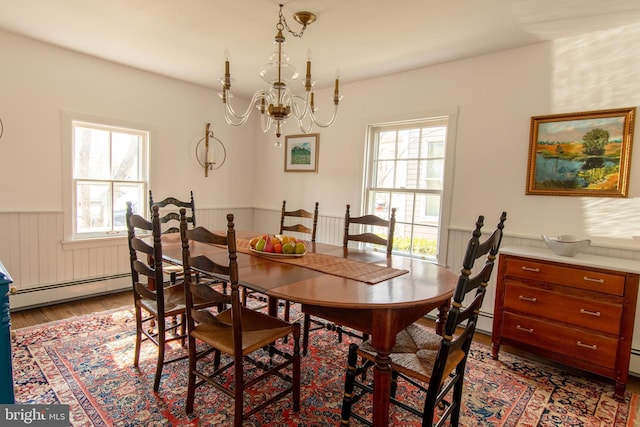 dining room featuring a healthy amount of sunlight, light wood finished floors, a chandelier, and wainscoting