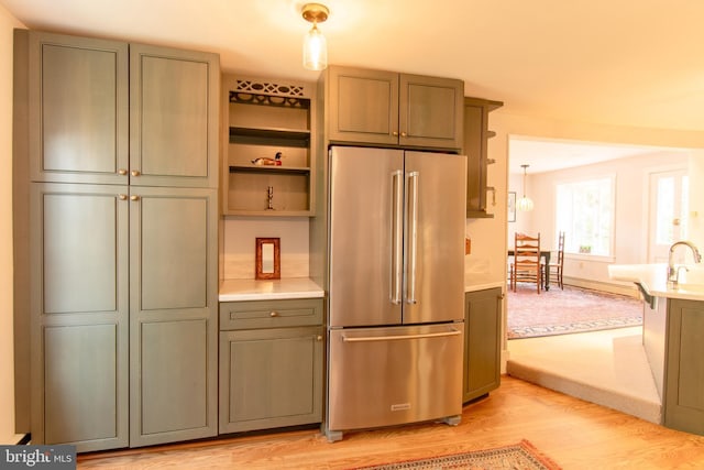 kitchen with green cabinets, light countertops, high end refrigerator, and light wood-style floors