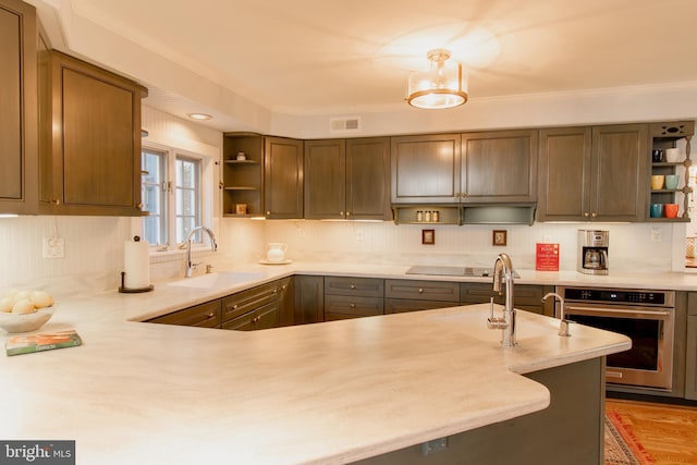 kitchen featuring open shelves, light countertops, visible vents, a sink, and oven