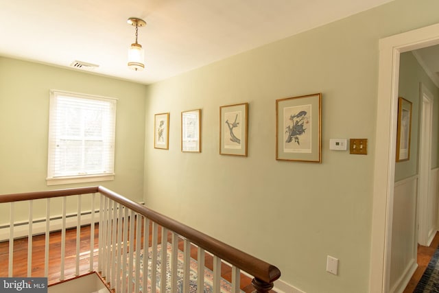 hallway featuring an upstairs landing, visible vents, and baseboard heating