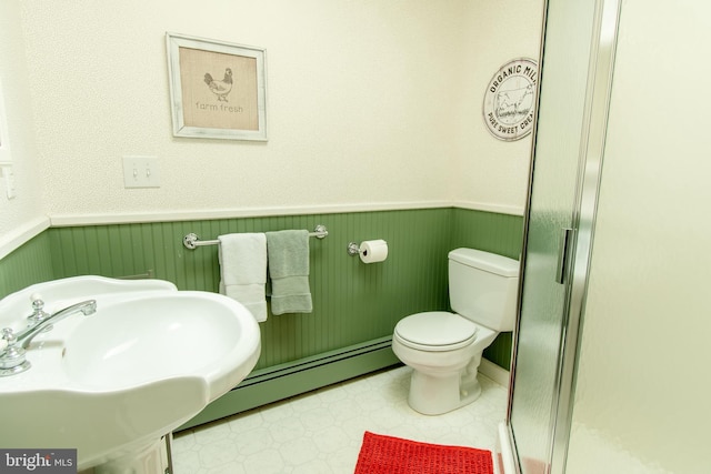 full bath with toilet, a baseboard heating unit, a sink, and wainscoting