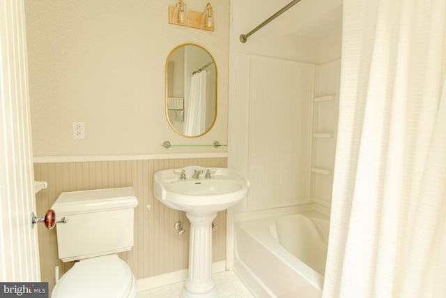 bathroom featuring shower / bath combo, wainscoting, and toilet