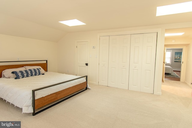 bedroom featuring a baseboard heating unit, vaulted ceiling, a closet, and light colored carpet