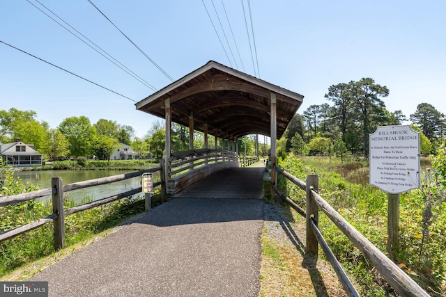 surrounding community featuring a detached carport, a water view, fence, and driveway