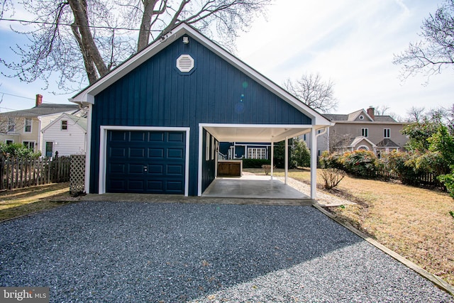 garage with gravel driveway, fence, and a detached garage