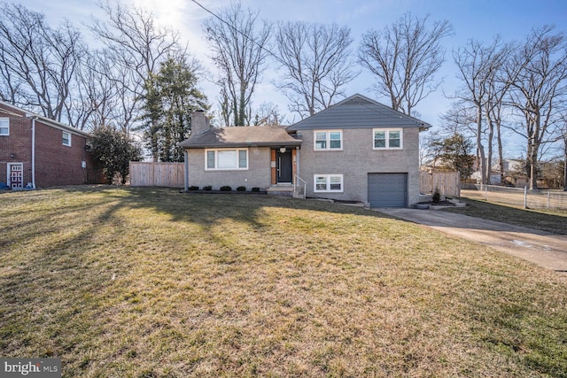 split level home with driveway, a chimney, an attached garage, fence, and a front lawn