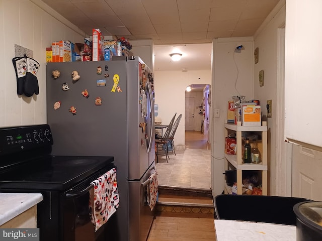 kitchen with arched walkways, electric range, and light wood-style flooring