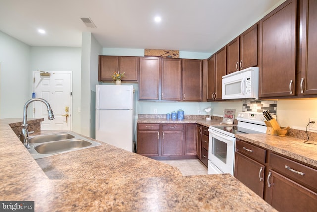 kitchen featuring tasteful backsplash, light countertops, visible vents, a sink, and white appliances