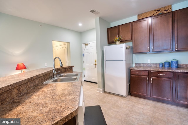 kitchen with freestanding refrigerator, visible vents, and a sink