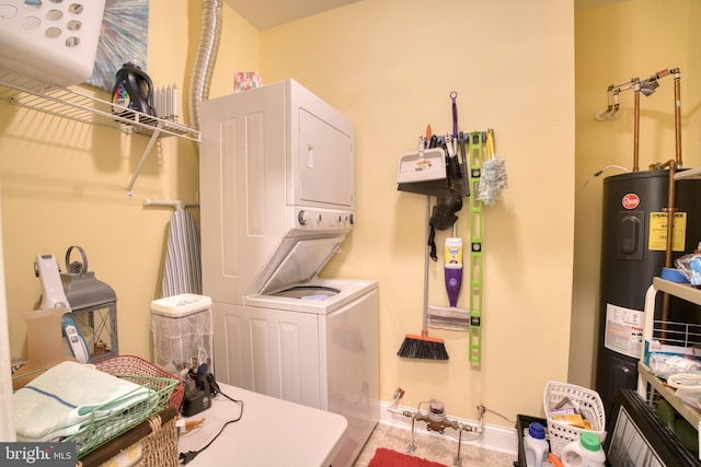 laundry area featuring water heater, laundry area, stacked washer and dryer, and baseboards
