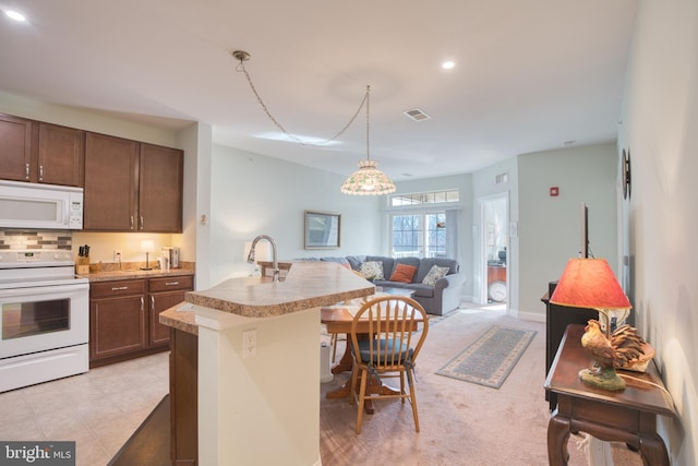 kitchen with a breakfast bar area, white appliances, visible vents, open floor plan, and light countertops