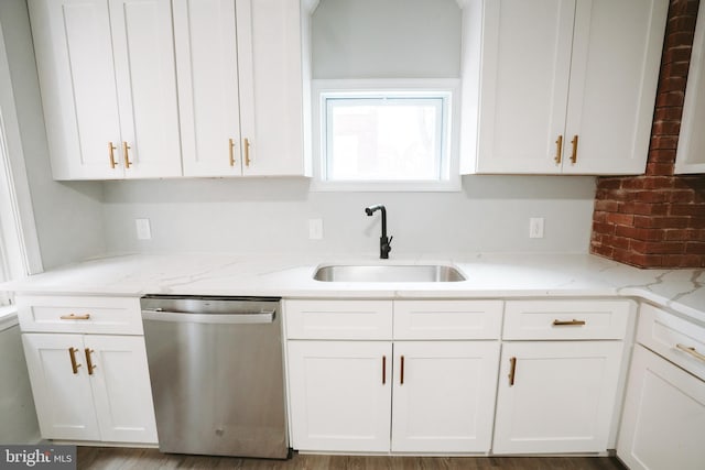 kitchen with white cabinetry, a sink, stainless steel dishwasher, and light stone countertops