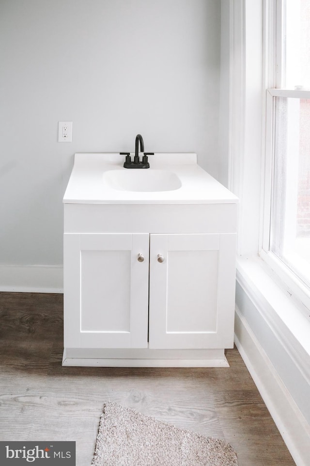 bathroom featuring plenty of natural light, baseboards, wood finished floors, and vanity