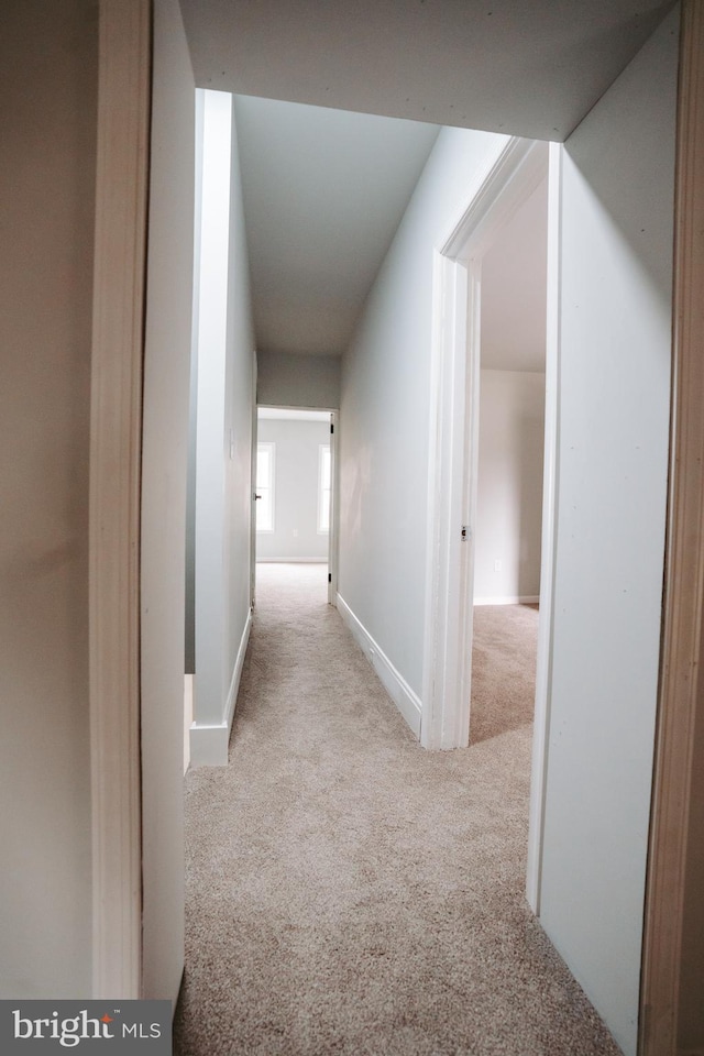 corridor featuring light carpet and baseboards