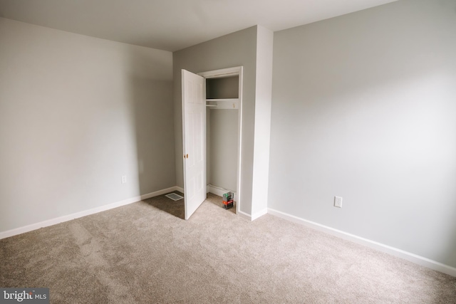 unfurnished bedroom featuring light carpet, a closet, and baseboards