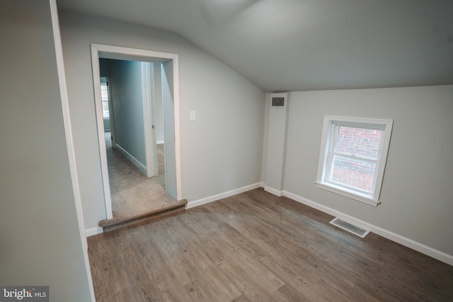 interior space featuring baseboards, visible vents, vaulted ceiling, and wood finished floors