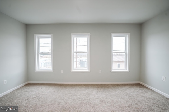 spare room featuring carpet, plenty of natural light, and baseboards