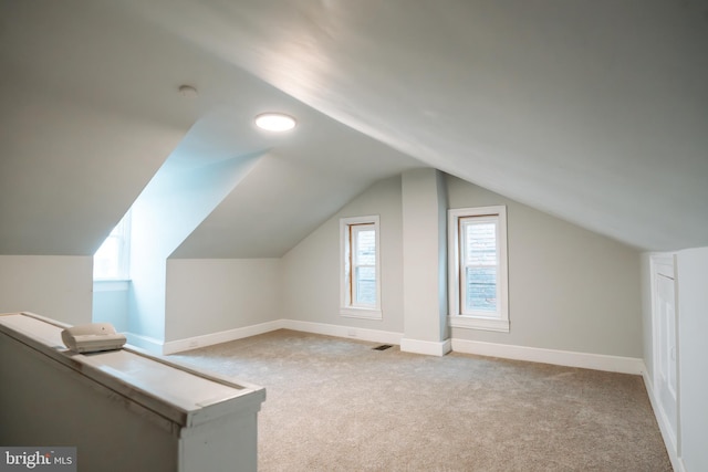 additional living space with lofted ceiling, light carpet, visible vents, and baseboards