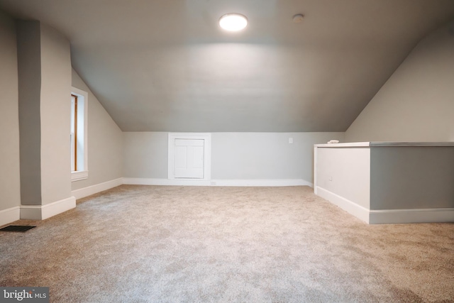 bonus room featuring baseboards, lofted ceiling, visible vents, and light colored carpet