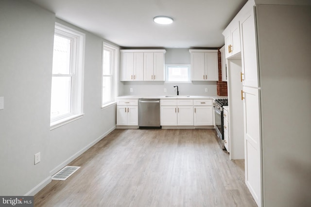 kitchen featuring stainless steel appliances, light countertops, white cabinets, and a sink