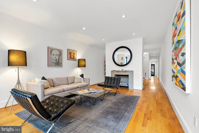 living room with light wood-type flooring, a fireplace, baseboards, and recessed lighting