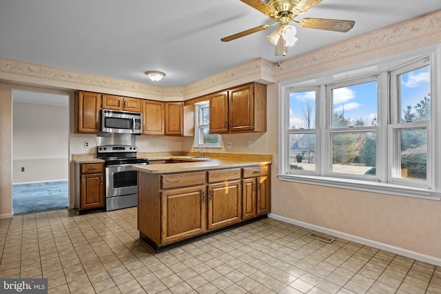 kitchen featuring visible vents, appliances with stainless steel finishes, brown cabinets, a peninsula, and light countertops