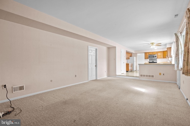 unfurnished living room with baseboards, visible vents, and light colored carpet