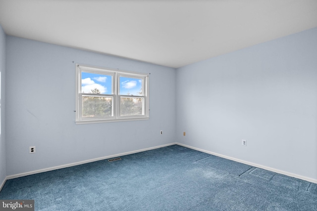 unfurnished room with dark colored carpet, visible vents, and baseboards