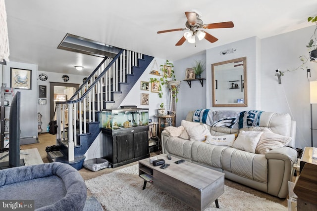 living room with stairs, carpet floors, and a ceiling fan